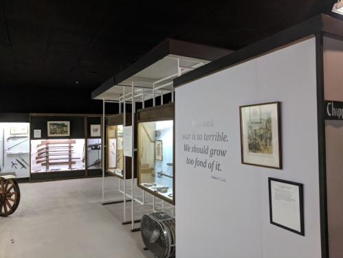 Museum exhibit featuring historical weapons and a quote about the horrors of war on a wall.