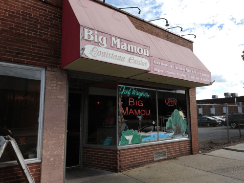 Exterior of Big Mamou restaurant, featuring a red awning and neon "Open" sign, showcasing Louisiana cuisine.