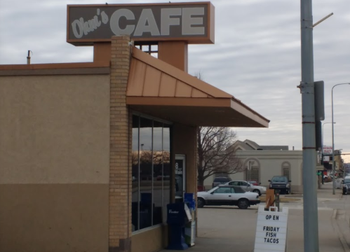 Exterior of Ohm's Cafe with a sign advertising Friday fish tacos and a cloudy sky in the background.
