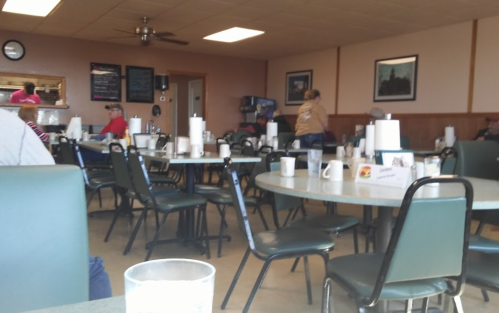 A casual diner interior with empty tables, chairs, and patrons in the background, featuring a relaxed atmosphere.