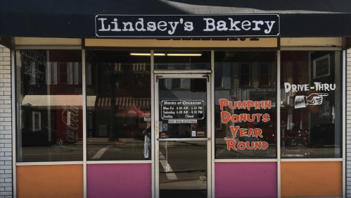Front view of Lindsey's Bakery featuring a drive-thru, with signs for pumpkin donuts and hours of operation.