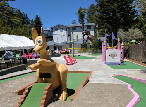 A colorful mini-golf course featuring a large kangaroo statue and whimsical castle structures in a sunny outdoor setting.