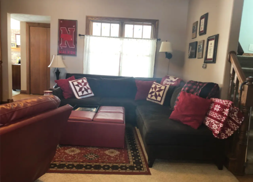 Cozy living room with a sectional sofa, decorative pillows, and framed photos on the walls, featuring warm colors.