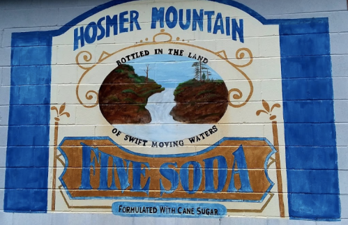 Mural featuring "Hosmer Mountain Fine Soda," with a scenic landscape and the phrase "Bottled in the land of swift moving waters."