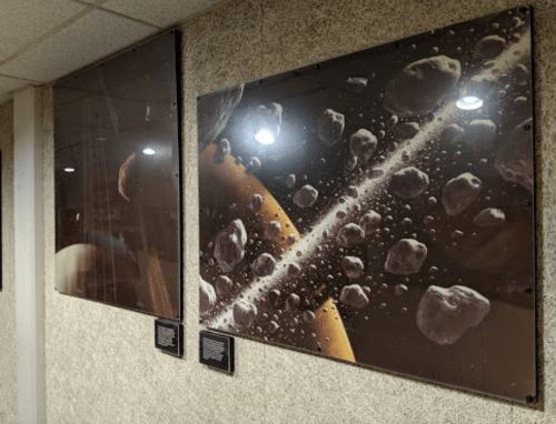 Two framed space-themed images on a textured wall, featuring celestial bodies and a ringed planet.