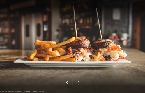 A plate with two sliders and a side of crispy fries on a rustic table in a restaurant setting.