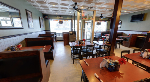 Interior of a cozy restaurant featuring booths, tables, and festive decorations. Bright and inviting atmosphere.