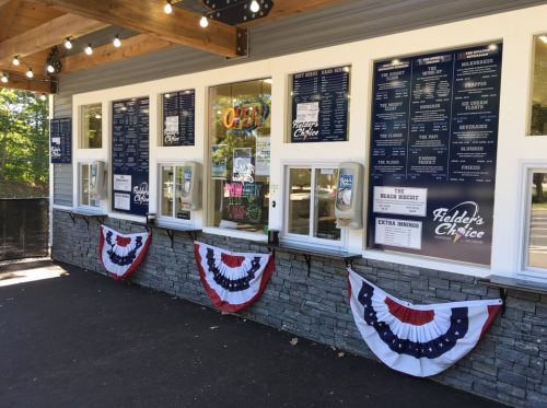 A food stand with a menu displayed on the wall and patriotic bunting underneath the windows.