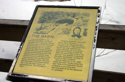 A weathered informational sign about "The Basin," featuring a historical description and a portrait of Henry David Thoreau.