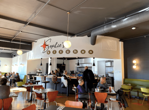 Interior of Sophie's Kitchen, featuring a modern dining area with patrons, a counter, and stylish decor.