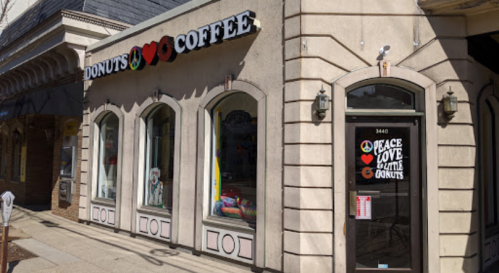A cozy donut and coffee shop with colorful signage and large windows, featuring a welcoming entrance.