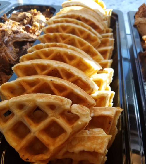 A row of golden-brown waffles arranged neatly in a tray.