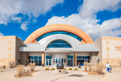 Exterior view of Anderson Regional Airport with a modern design, featuring a large arch and blue skies in the background.