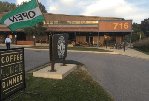 A building with a large sign reading "716," a flag that says "OPEN," and a sign for coffee, lunch, and dinner.