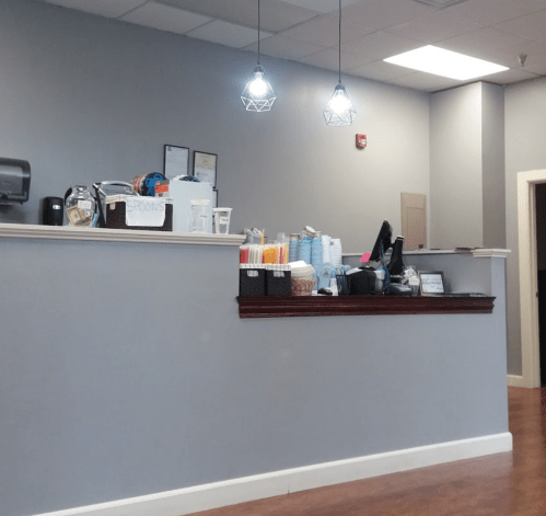 A modern reception area with a counter, decorative lights, and organized supplies in baskets.