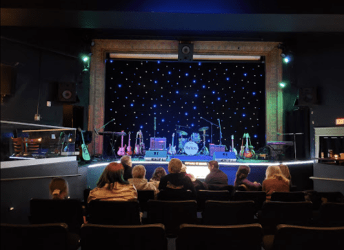 A stage with musical instruments and lights, viewed from the audience seating area.