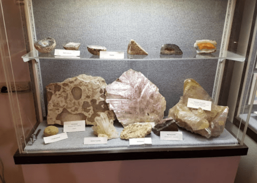 A display case featuring various colorful rocks and minerals, each labeled with their names.