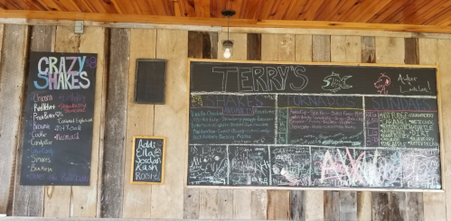 Chalkboard menu at Terry's featuring shakes, tornadoes, and sundaes, with colorful writing on a rustic wooden wall.