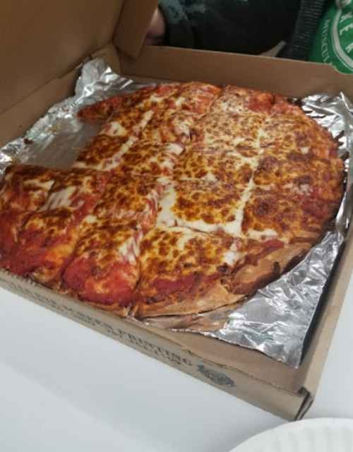 A pizza in a cardboard box, topped with melted cheese and pepperoni, resting on foil.