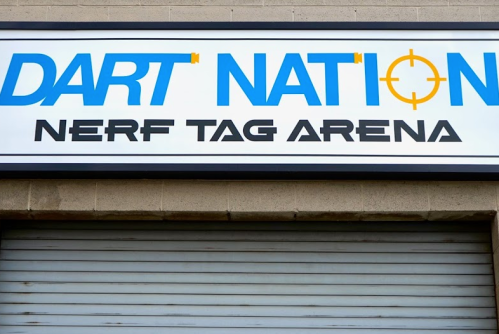 Sign for "Dart Nation" Nerf Tag Arena, featuring bold blue and black lettering on a white background.
