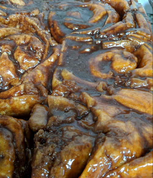 Close-up of sticky, caramelized cinnamon rolls with a glossy glaze, showcasing swirls and rich texture.