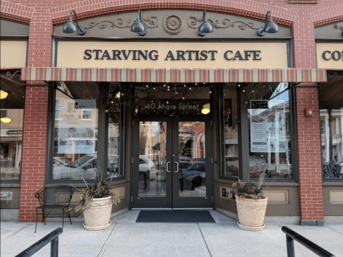 Entrance of the Starving Artist Cafe, featuring large glass doors and decorative planters, located at 40 Main Street.