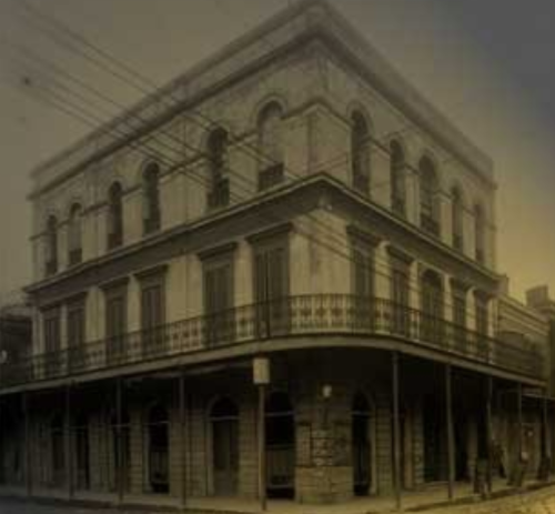 Historic building with a balcony, featuring arched windows and a faded, vintage appearance.