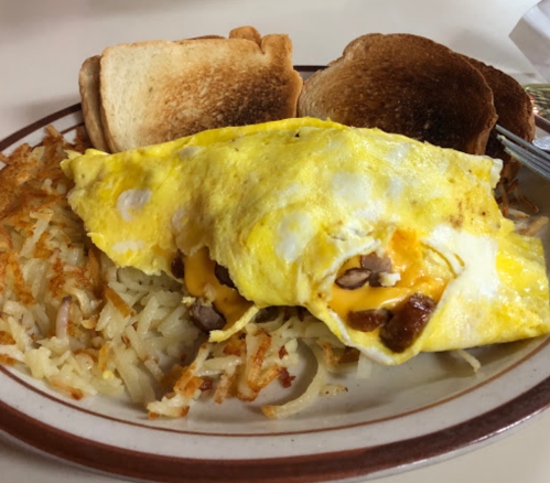 A plate with a cheese omelette, crispy hash browns, and two slices of toasted bread.