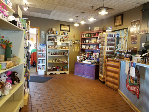 A cozy gift shop interior with shelves of souvenirs, plush toys, and a colorful checkout counter.