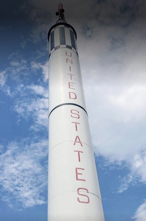 A tall rocket with "UNITED STATES" written on its side, set against a blue sky with clouds.