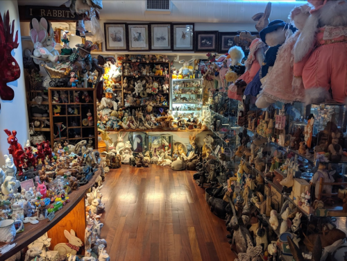 A cozy shop filled with various stuffed animals and decorative figurines, showcasing a warm wooden floor and shelves.