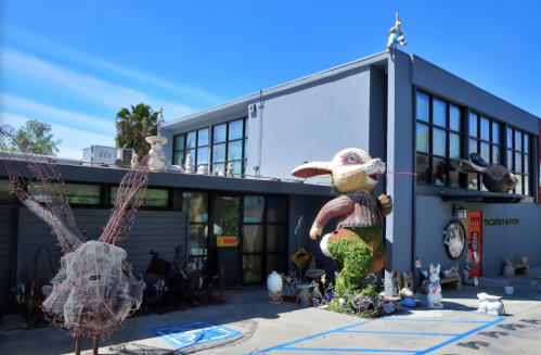 A whimsical building featuring a large rabbit sculpture and various eclectic decorations outside.