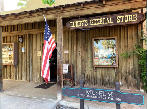 Entrance to Ruddy's General Store, featuring a wooden facade, an American flag, and a sign for a 1930s museum.