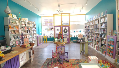 A colorful children's bookstore with shelves of books, a cozy reading area, and playful decor.