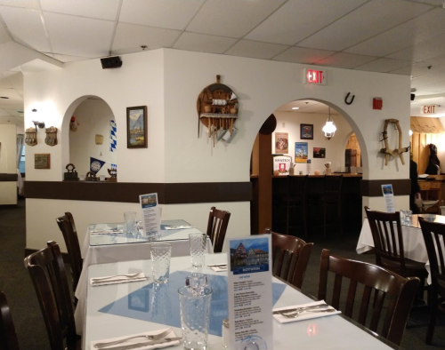Interior of a restaurant featuring wooden decor, tables set with glasses, and a cozy atmosphere.