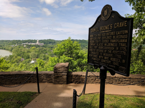A historical marker for Daniel Boone's grave overlooks a scenic view of a river and lush greenery.