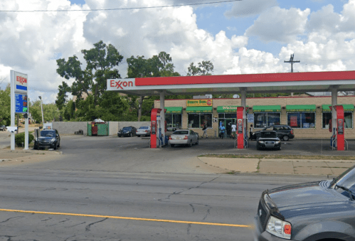 A busy Exxon gas station with cars parked outside, under a partly cloudy sky.