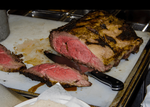 A perfectly cooked roast beef on a cutting board, with slices cut and a knife resting beside it.