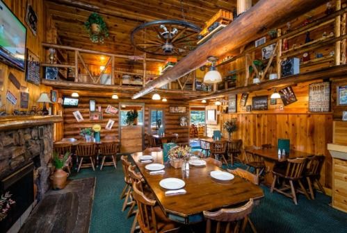 Cozy wooden restaurant interior with rustic decor, tables set for dining, and a warm, inviting atmosphere.