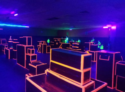 A dark room with glowing neon outlines of boxes and structures, creating a vibrant, illuminated play area.