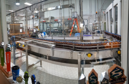 A brewery production line with bottles on a conveyor belt and equipment in a clean, industrial setting.