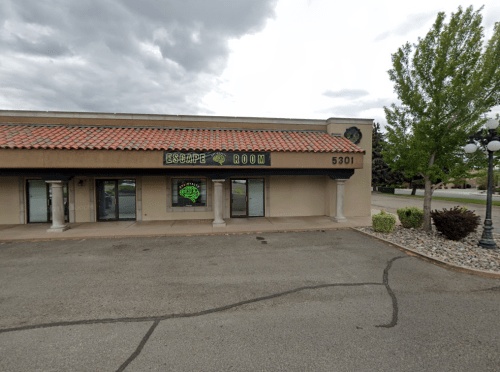 Exterior of an escape room building with a sign, located at 5301, under a cloudy sky.