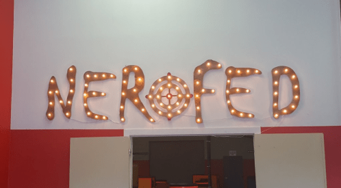 Neon-lit sign spelling "NEROFED" on a wall, with a target symbol in the center, above an open doorway.