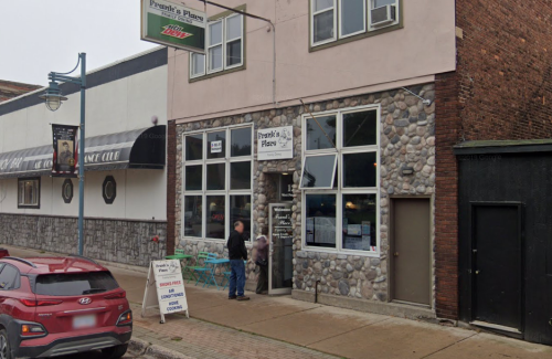 A stone-front building with large windows, featuring a sign for "Frank's Place." A person stands at the entrance.