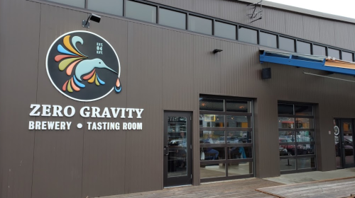 Exterior of Zero Gravity Brewery and Tasting Room, featuring a colorful logo and large glass entrance.