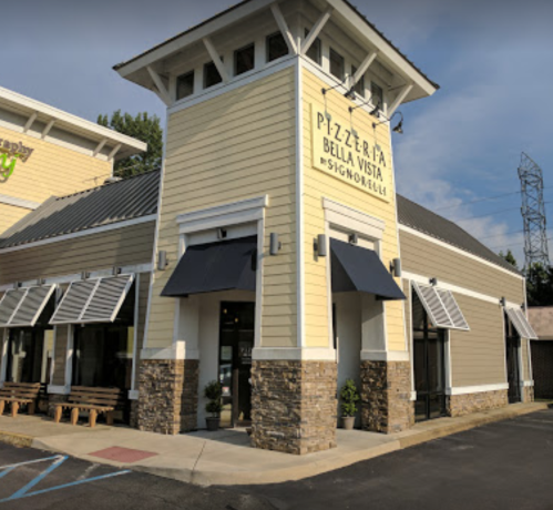 Exterior of a yellow building with a sign reading "Pizzeria Bella Vista," featuring awnings and stone accents.