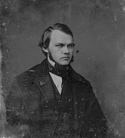 A vintage portrait of a young man with a serious expression, wearing 19th-century formal attire and a high collar.