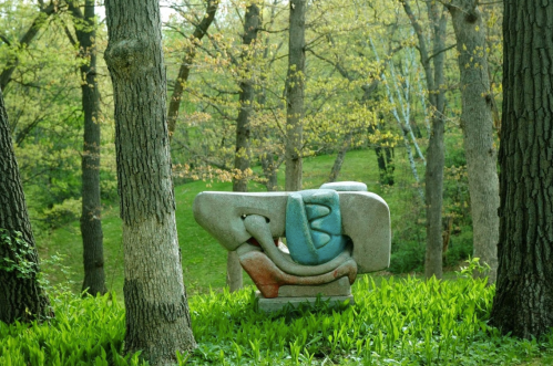 A colorful abstract sculpture nestled among trees and greenery in a serene forest setting.