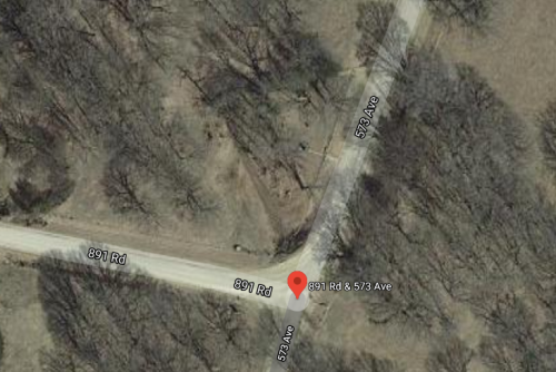 Aerial view of a road intersection labeled 891 Rd and 573 Ave, surrounded by trees and open land.