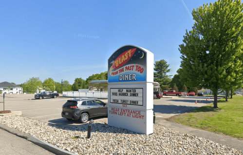 Sign for "Blast from the Past Too Diner" with job listings and directions, surrounded by a parking lot and trees.